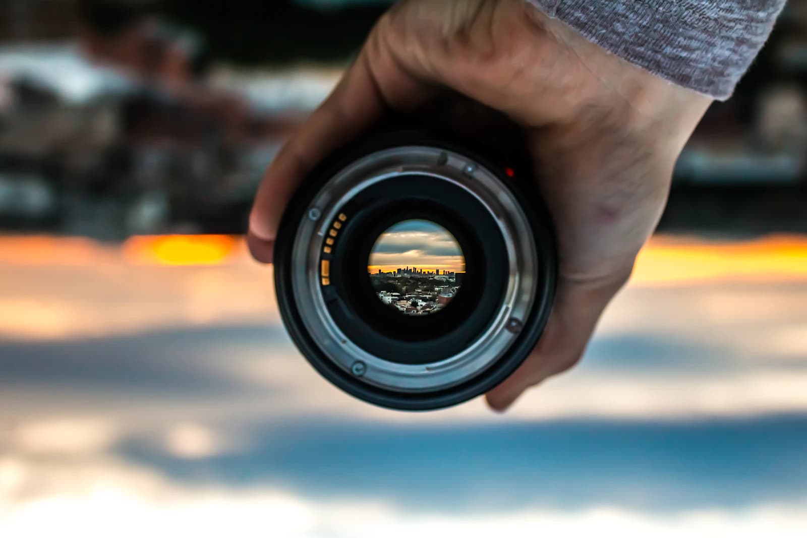 Hand holding a lens with an inverted city view visible through it