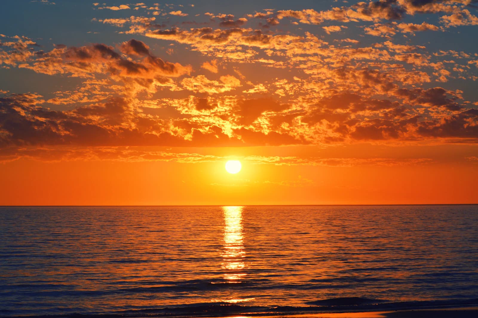 Sunset over the sea beneath orange clouds