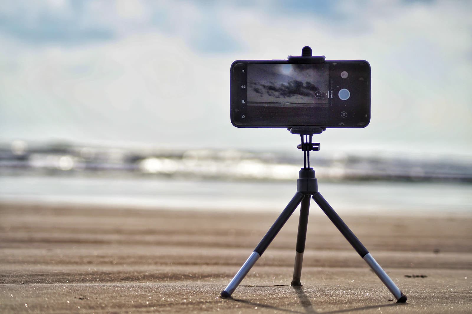 Smartphone mounted on a mini tripod on a sandy beach