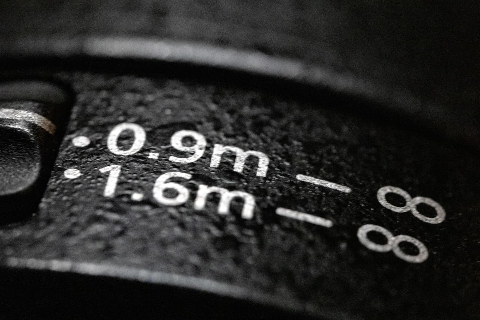 Close-up of a lens distance scale marked 0.9 m, 1.6 m and infinity