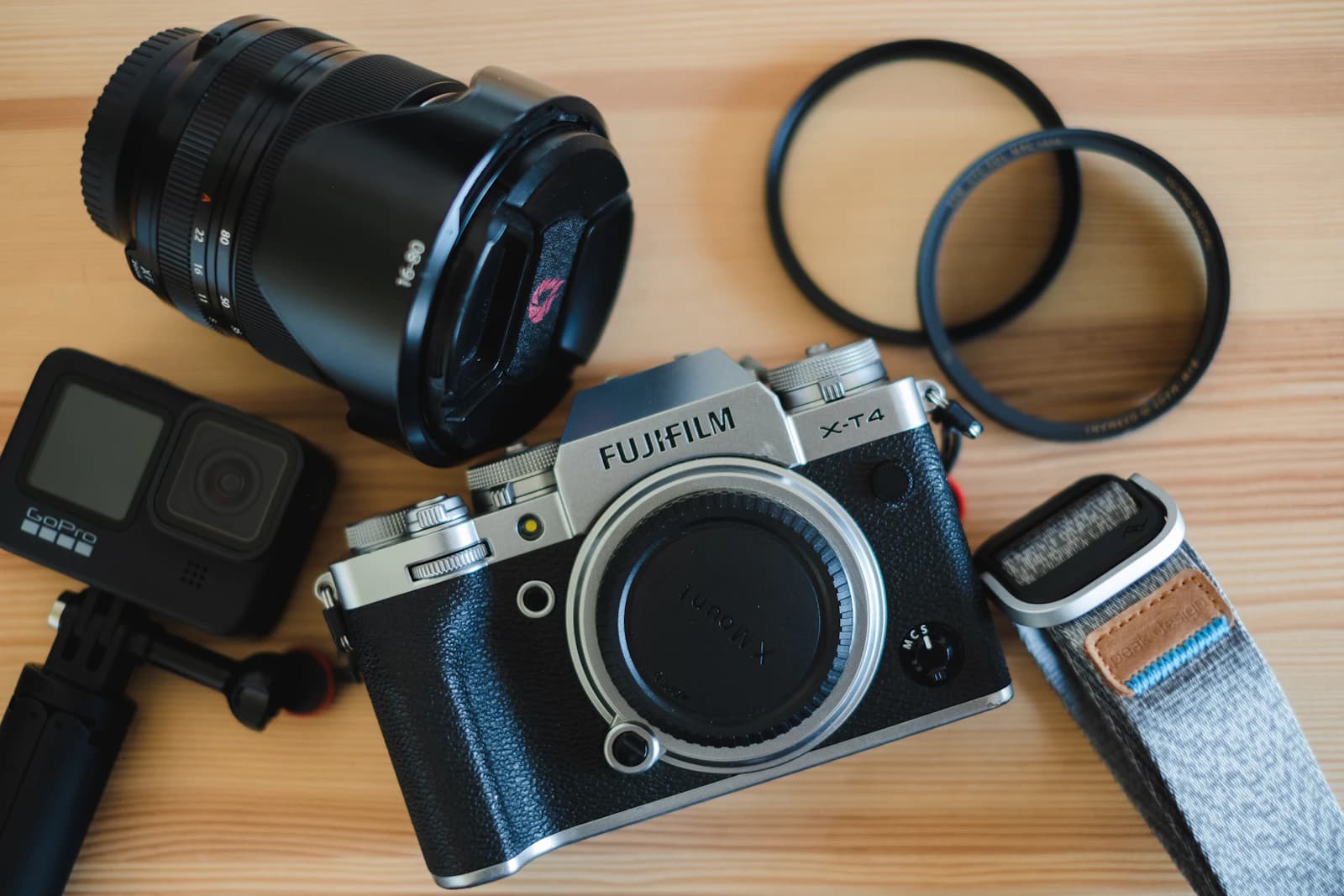 Camera body, lens, filter rings and an action camera on a wooden table