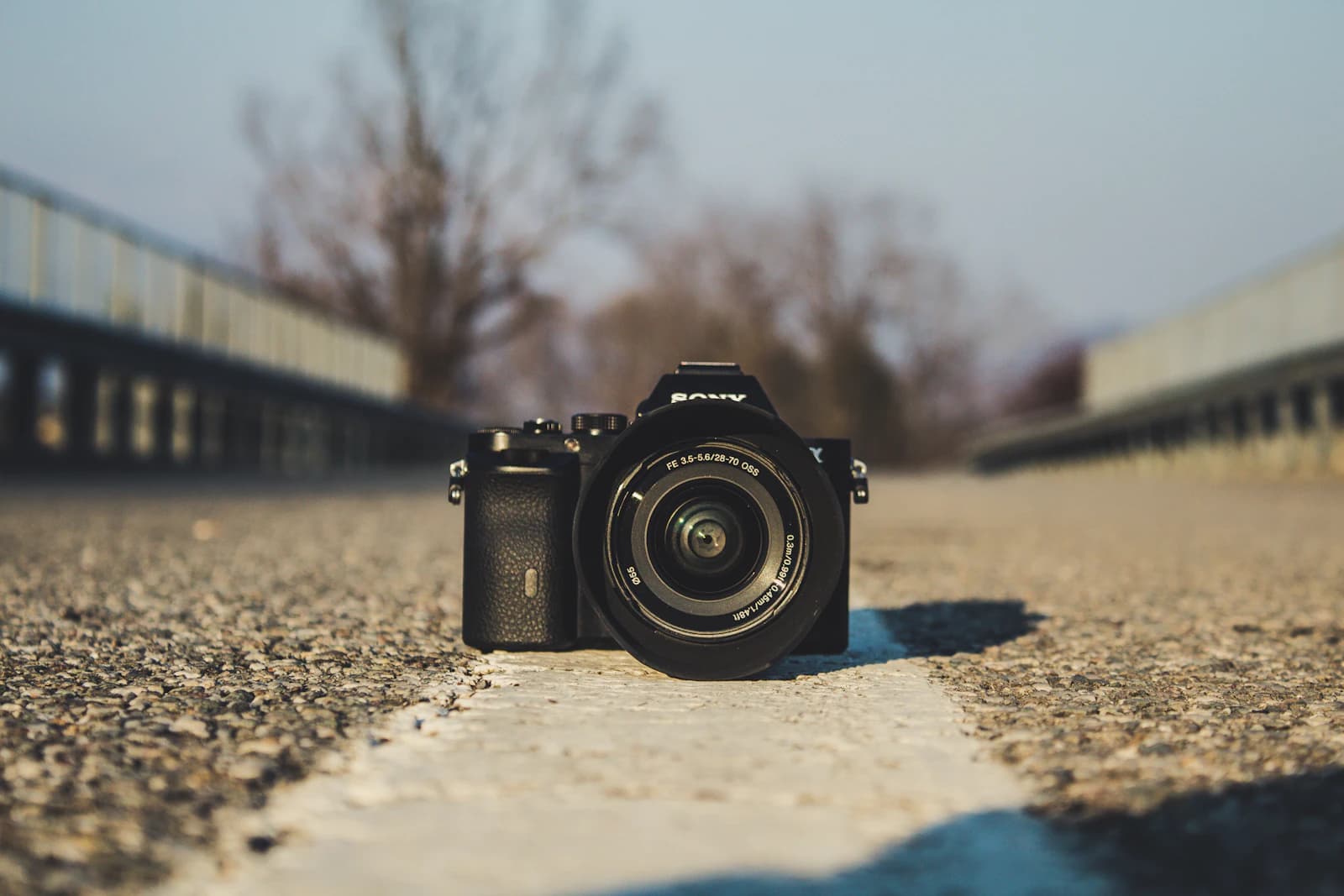 Low-angle shot of a mirrorless camera placed on a road's center line