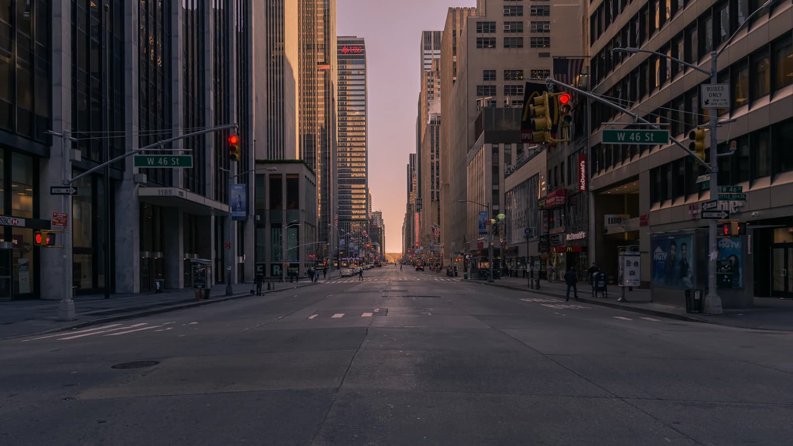 Empty city street between tall buildings at dusk