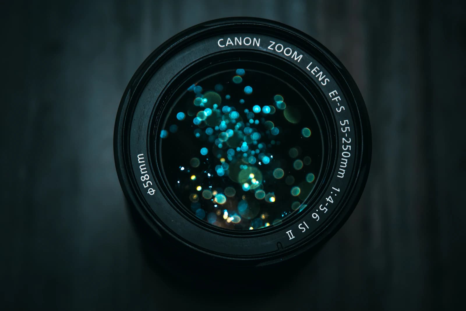 Front of a zoom lens with teal bokeh-like reflections on the glass